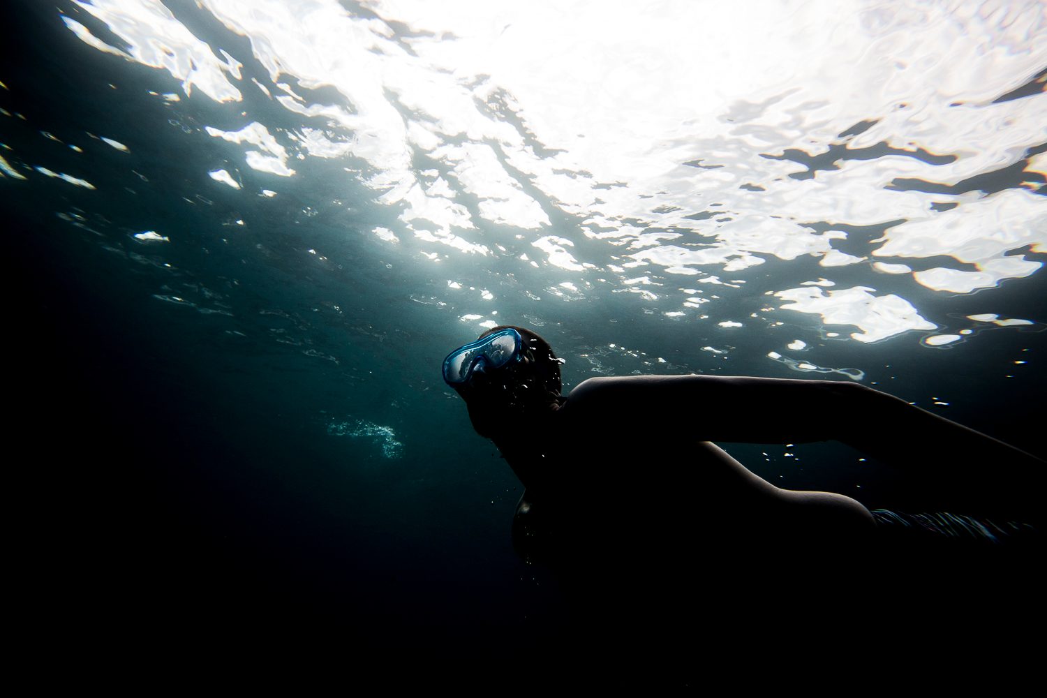Snorkeler silhouetted beneath the rippling ocean surface